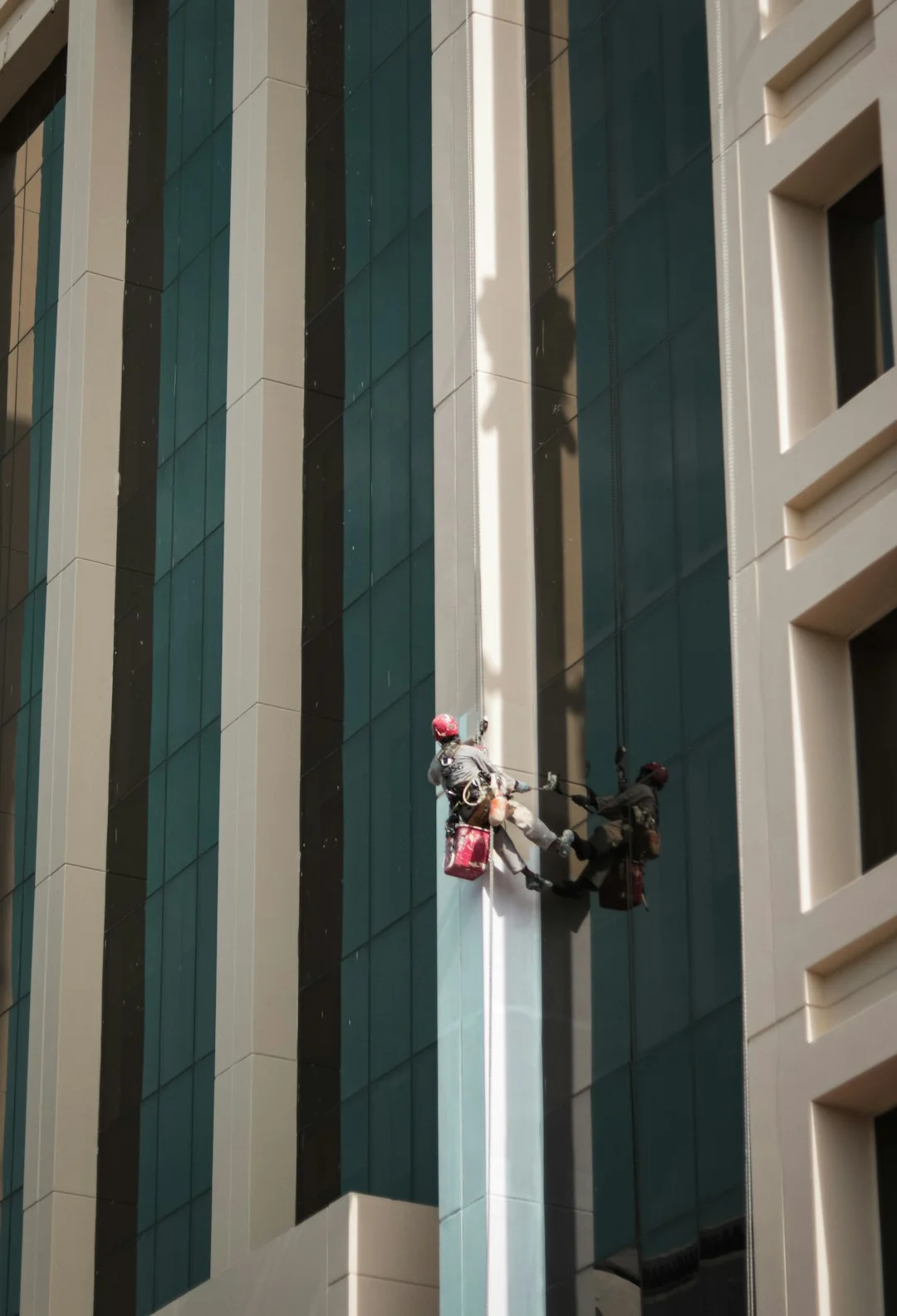 A man cleaning skyscraper windows with a harness, showcasing urban high-rise work.